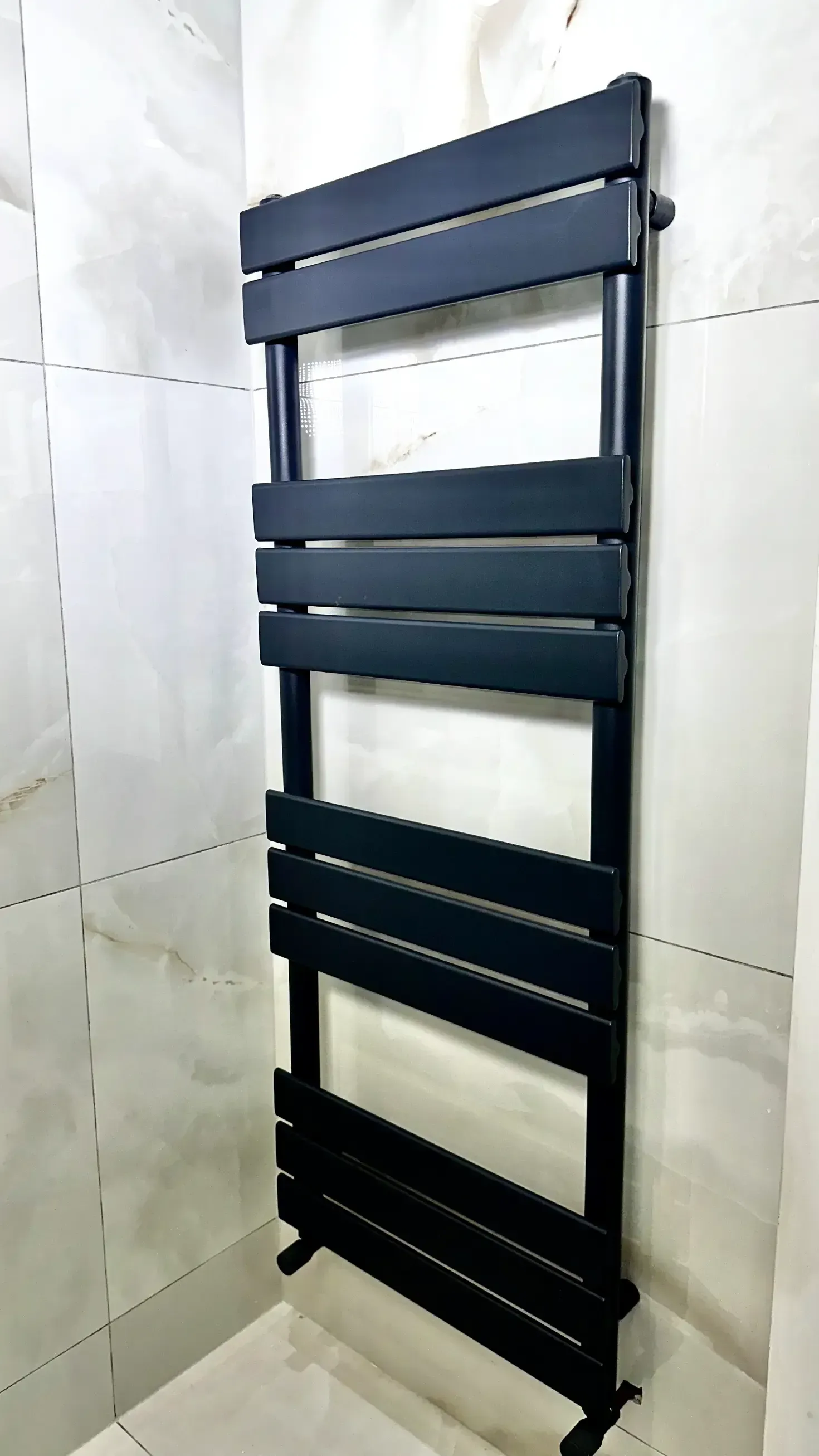 A black towel rack is hanging on a white wall in a bathroom.