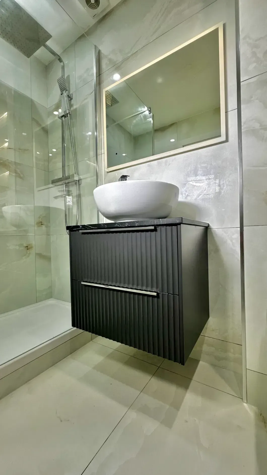 A bathroom with a sink , mirror and shower.