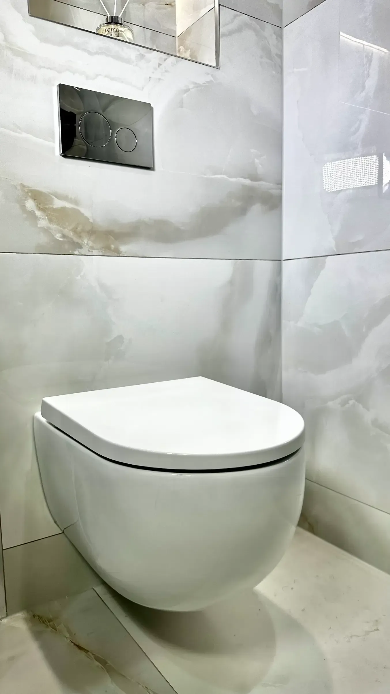 A white toilet is sitting on a tiled floor in a bathroom.