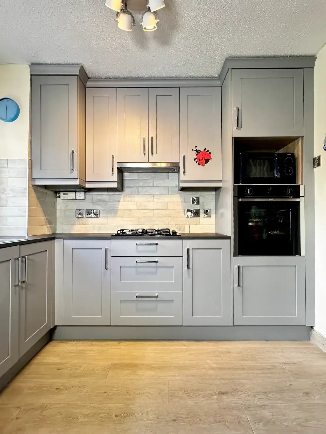 A kitchen with gray cabinets and a black oven