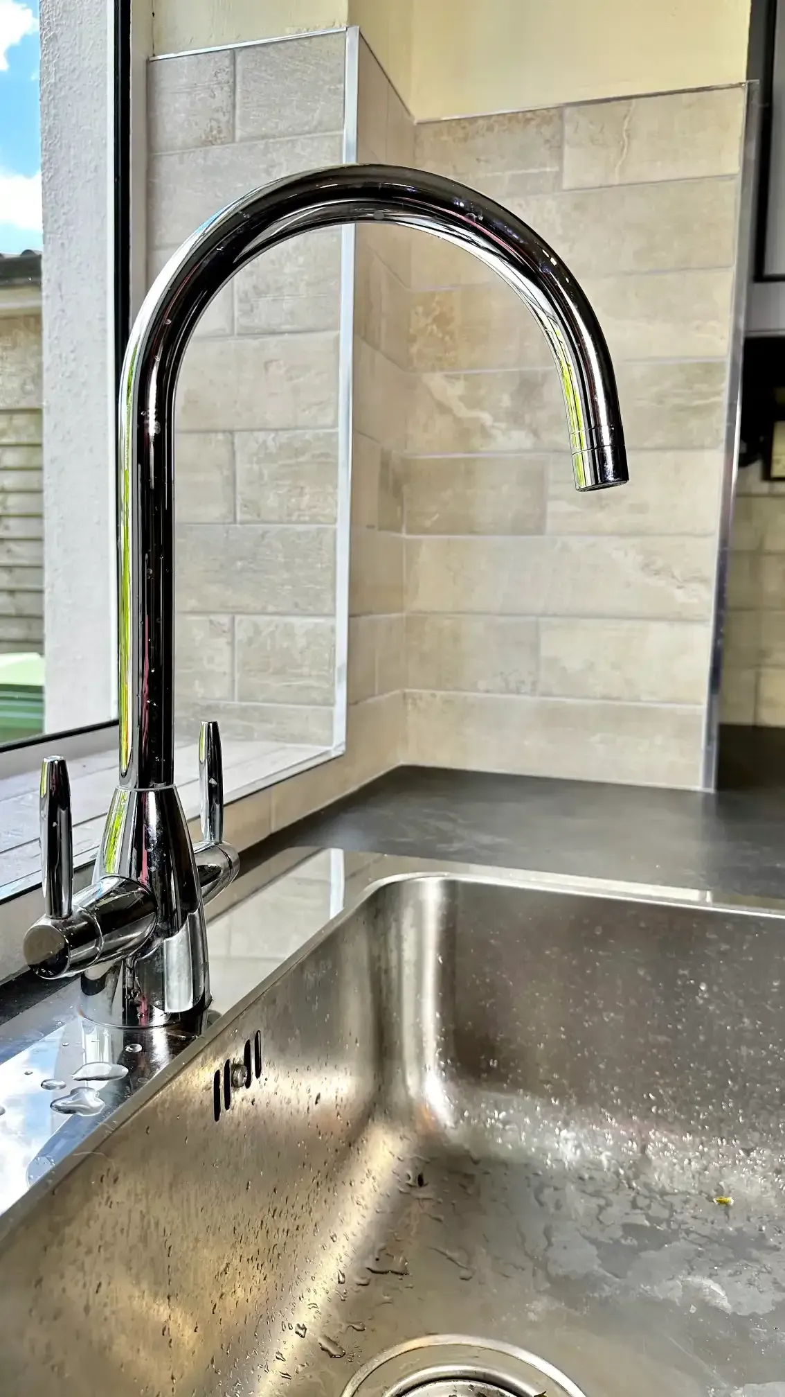 A close up of a stainless steel kitchen sink with a faucet.