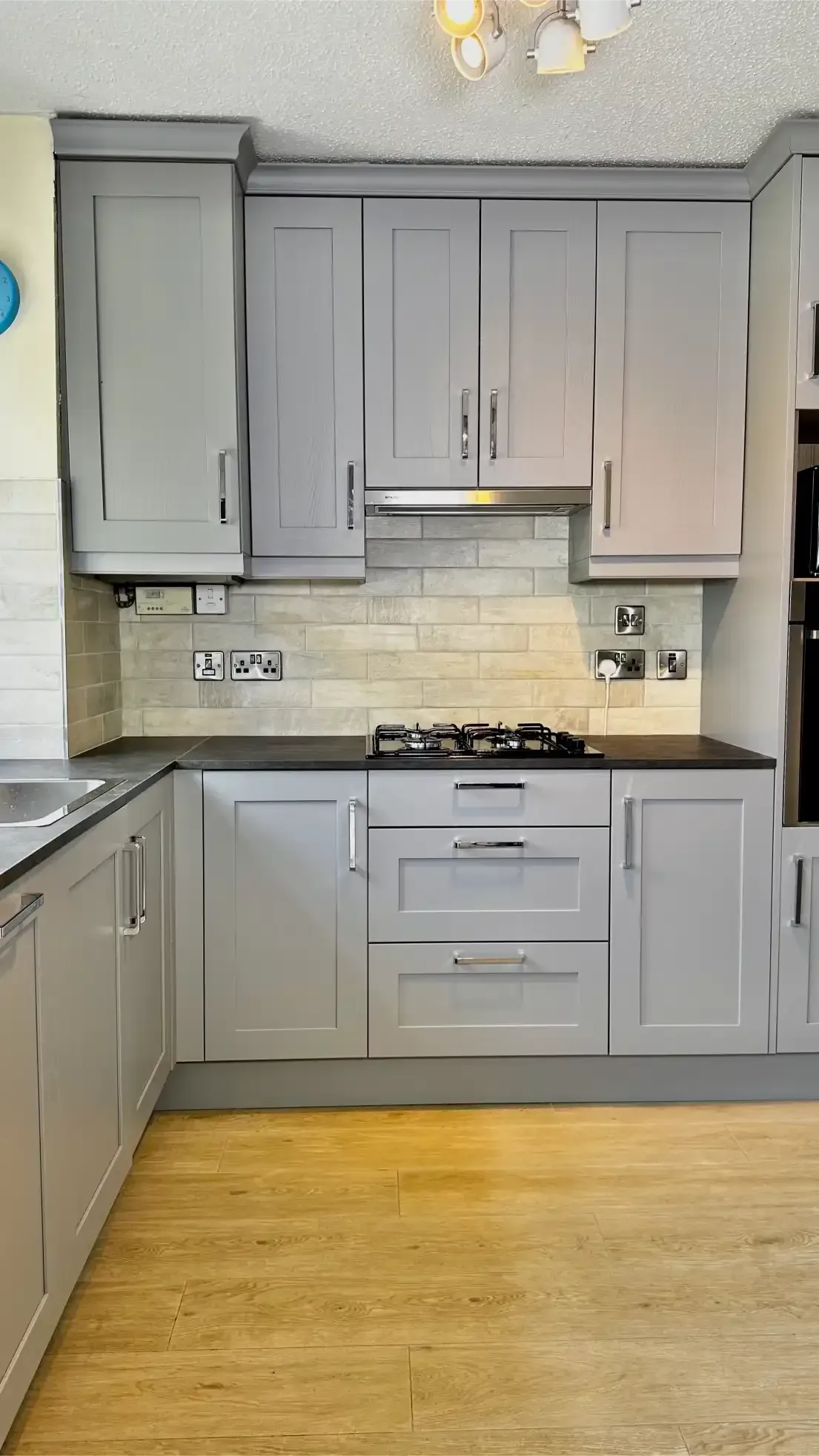 A kitchen with gray cabinets and a wooden floor.