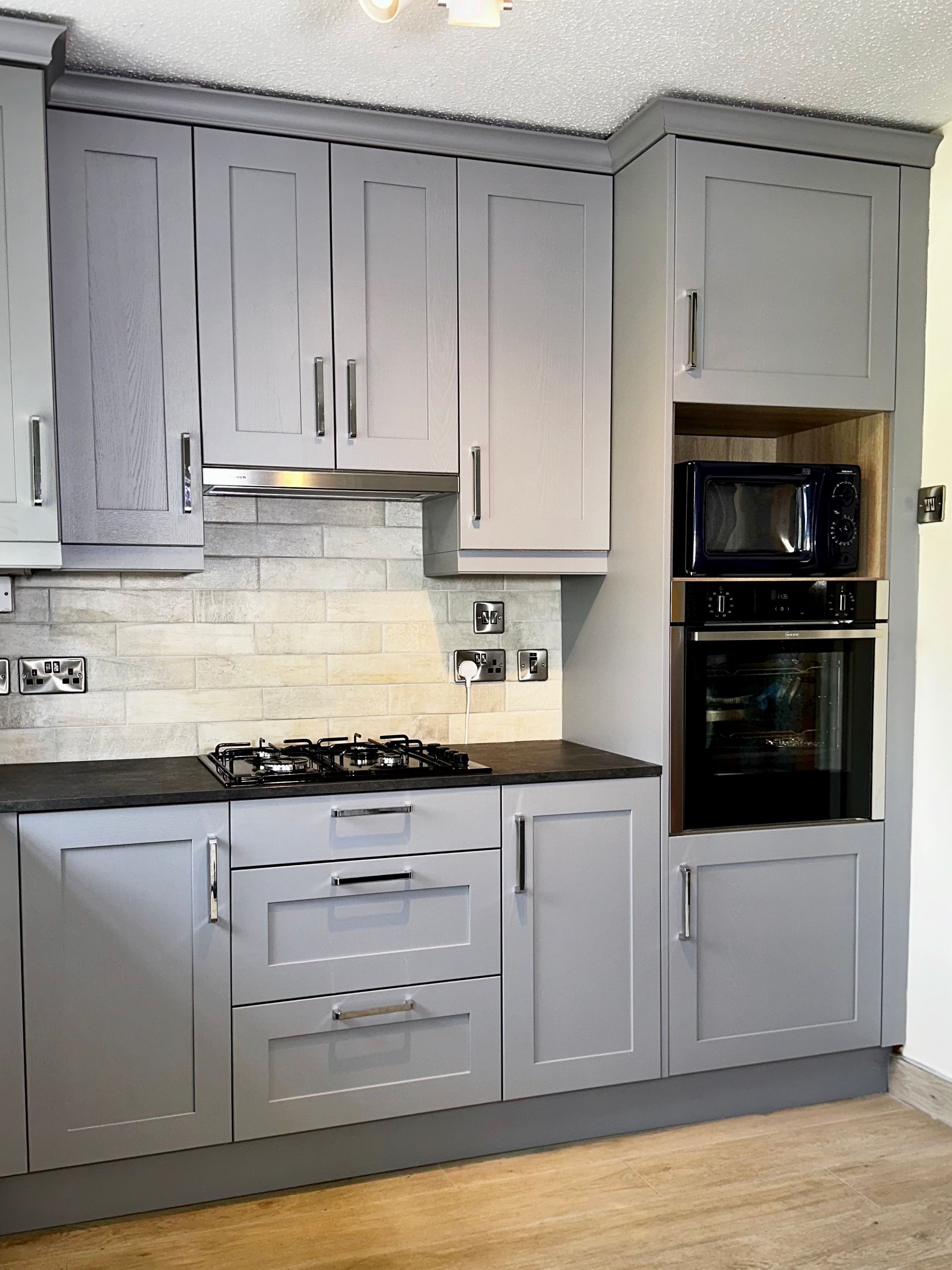 A kitchen with gray cabinets and black counter tops