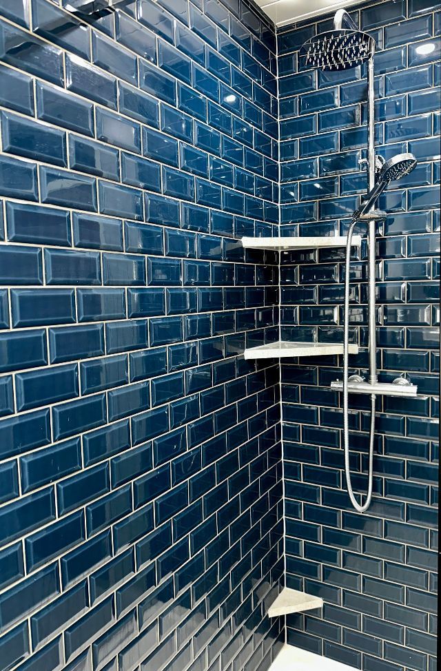 A shower with blue tiles and a shower head.