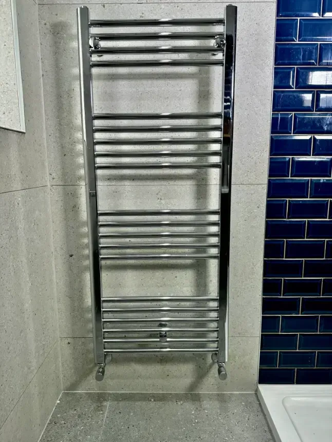 A chrome towel rack is hanging on a wall in a bathroom.