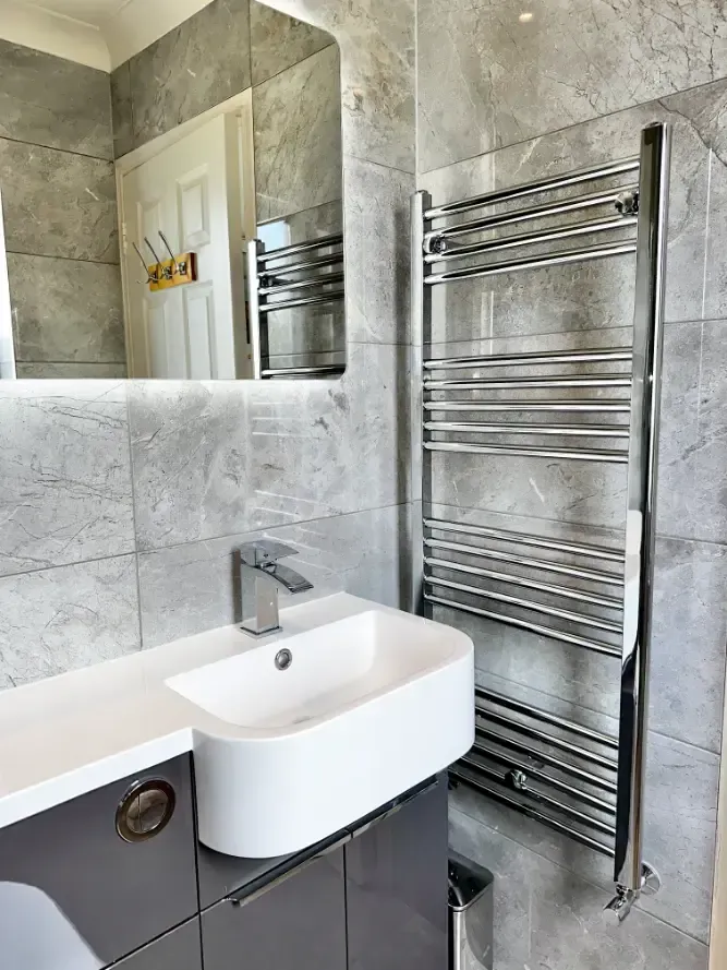 A bathroom with a sink , mirror and towel rack.