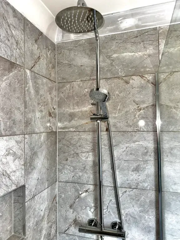 A shower head is hanging from the ceiling in a bathroom.