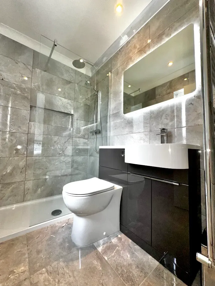 A bathroom with a toilet , sink , shower and mirror.