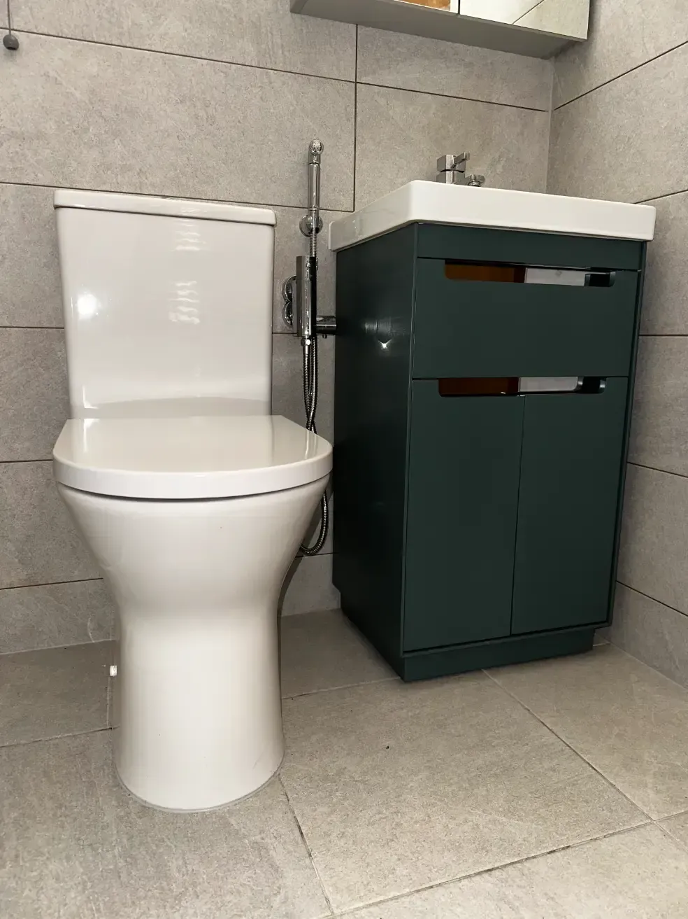 A bathroom with a toilet , sink and cabinet.