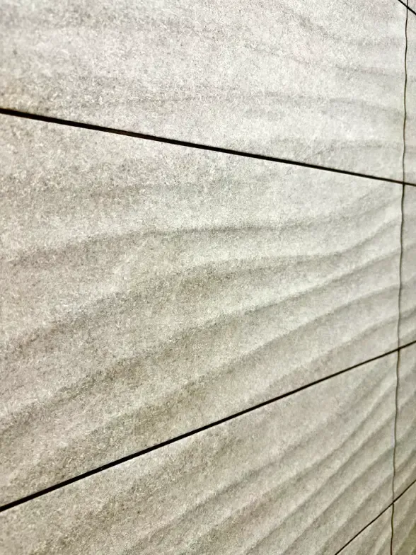 A close up of a tile wall with a wave pattern.