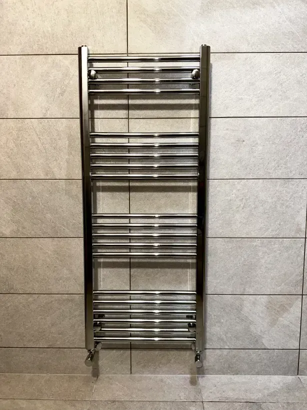A stainless steel towel rack is hanging on a tiled wall.