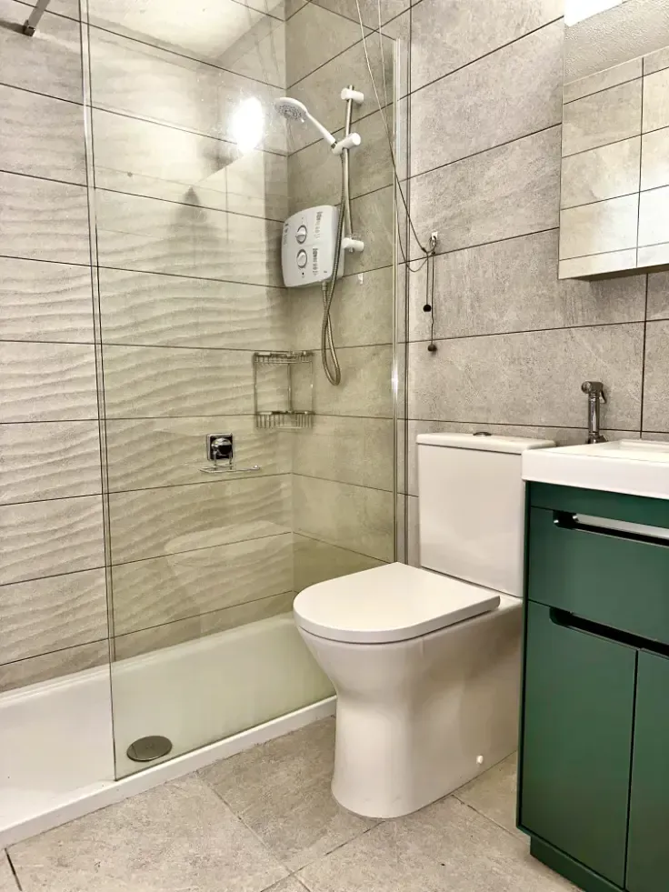 A bathroom with a toilet , sink and shower.