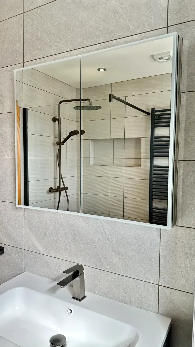 A bathroom with a sink , mirror and shower.