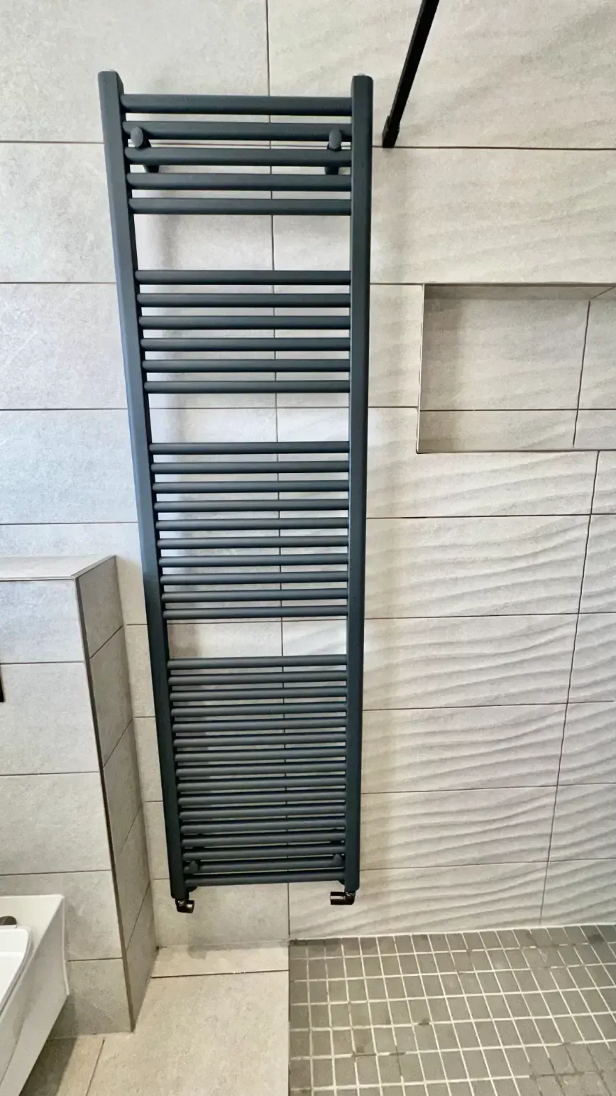 A black towel rack is hanging on a white tiled wall in a bathroom.