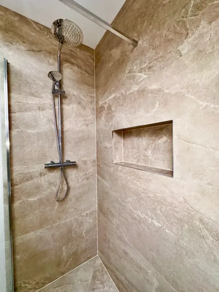 A shower with a shower head and a niche in the wall.