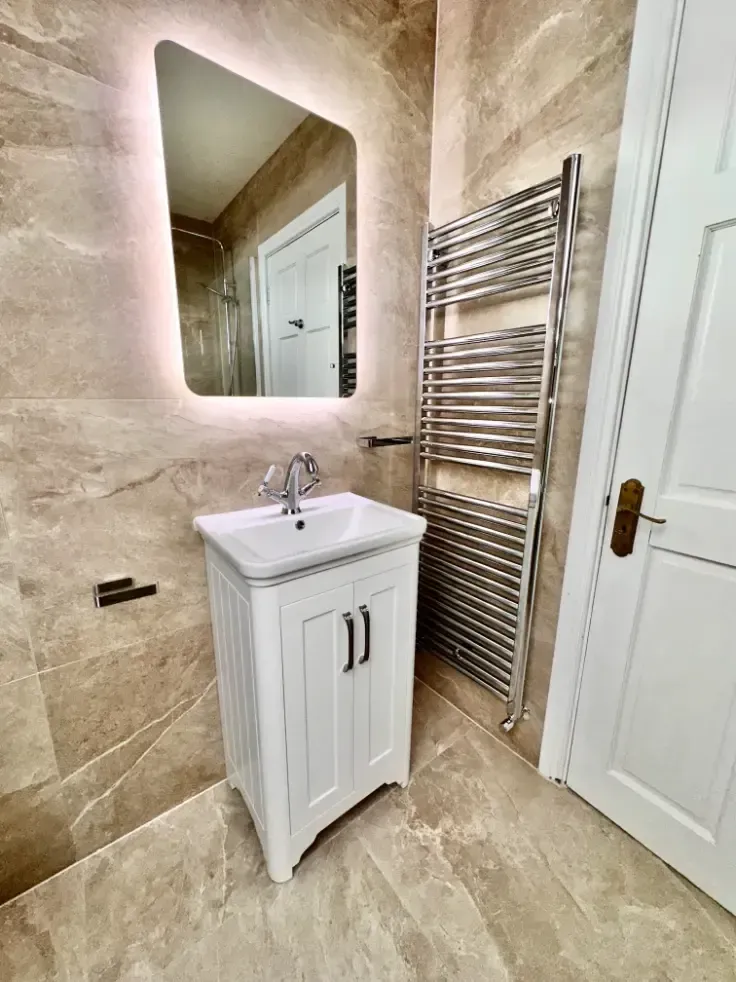 A bathroom with a sink , mirror and towel rack.