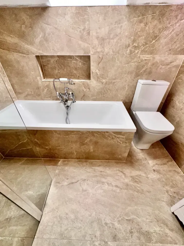 A bathroom with a bathtub , toilet and mirror.