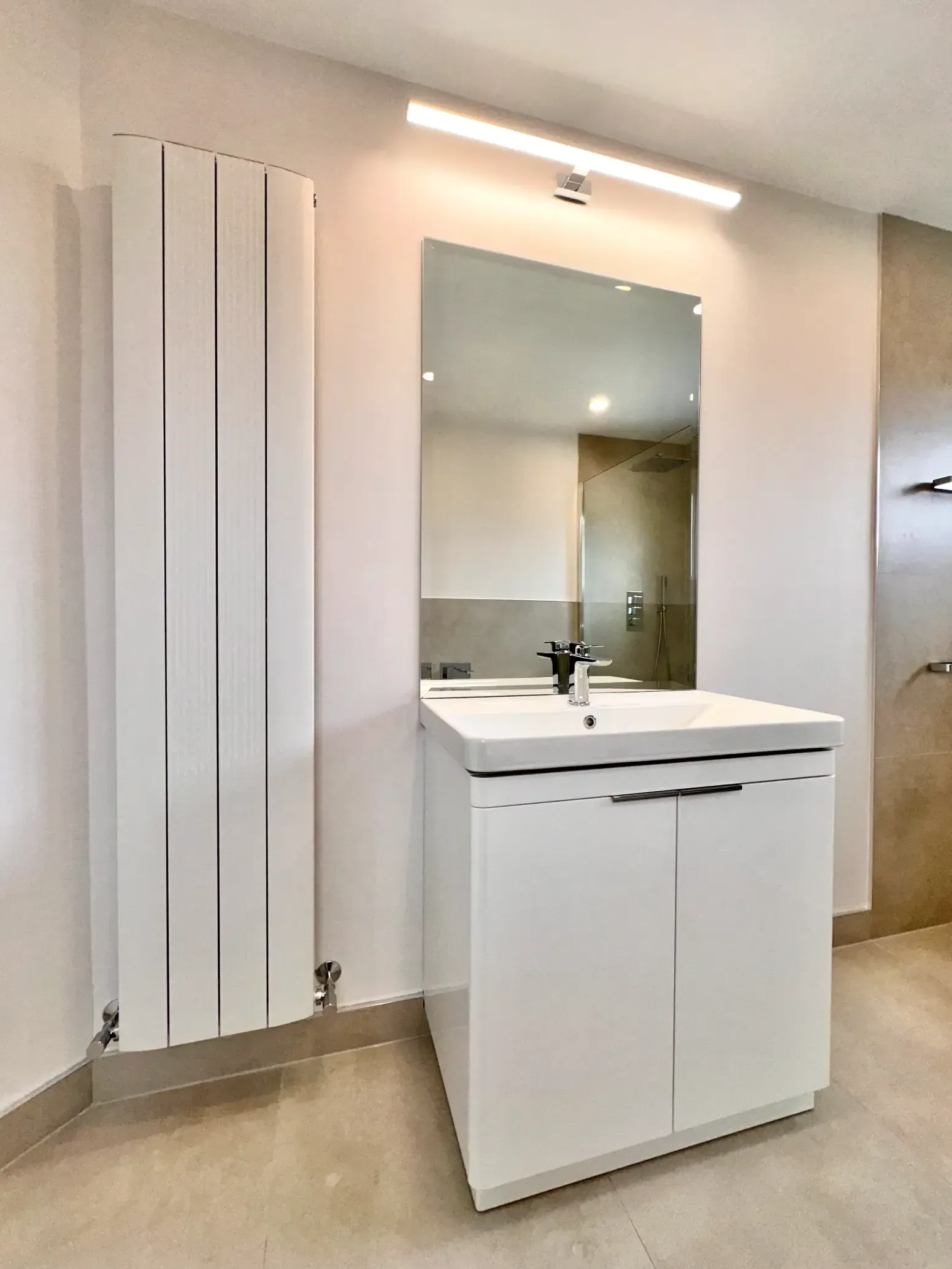 A bathroom with a sink , mirror and radiator.