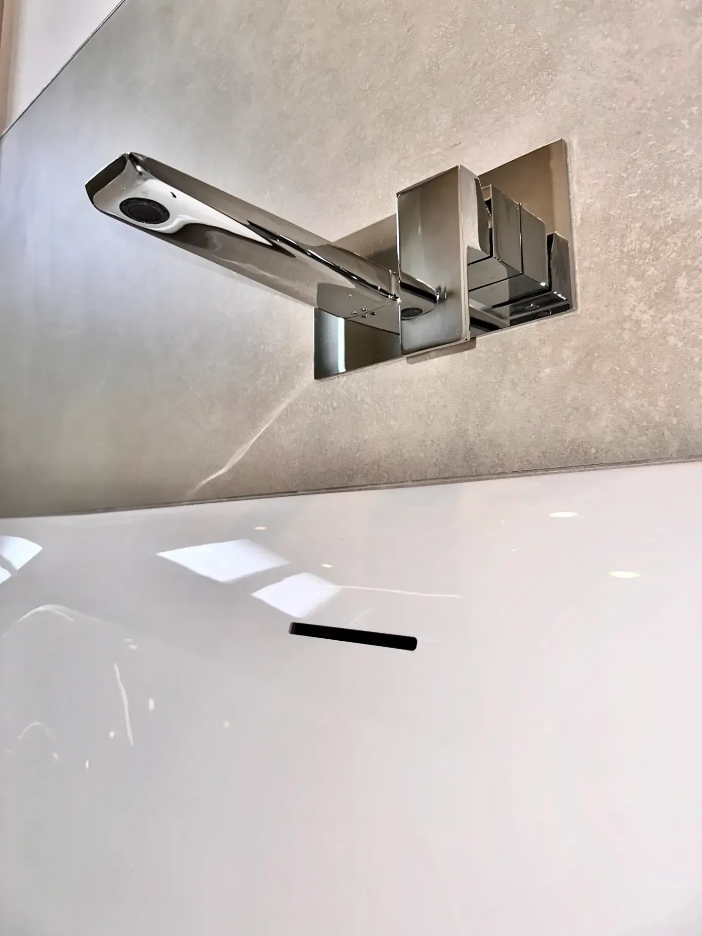 A faucet is hanging from the ceiling above a bathtub.