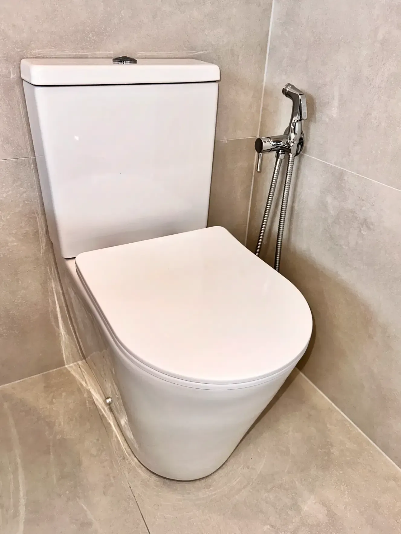 A toilet with a bidet attached to it in a bathroom.