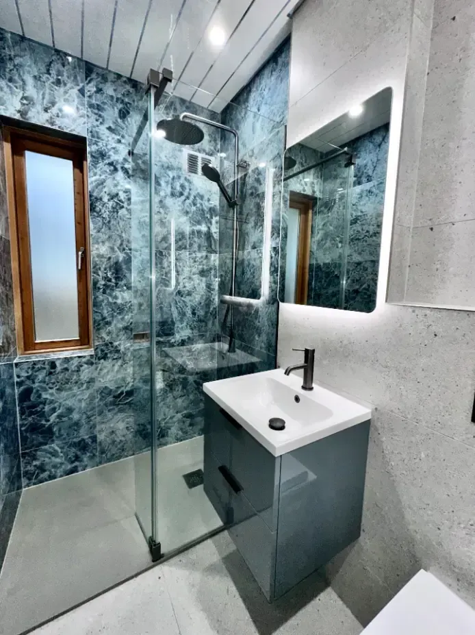A bathroom with a sink , toilet , shower and mirror.
