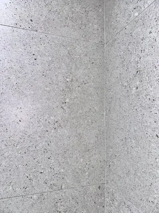 A close up of a white tile wall with a corner.