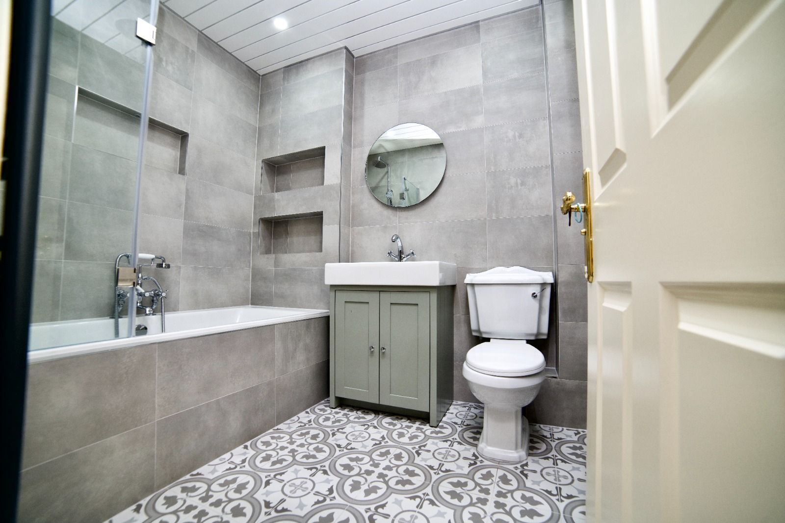 A bathroom with a toilet , sink , bathtub and mirror.