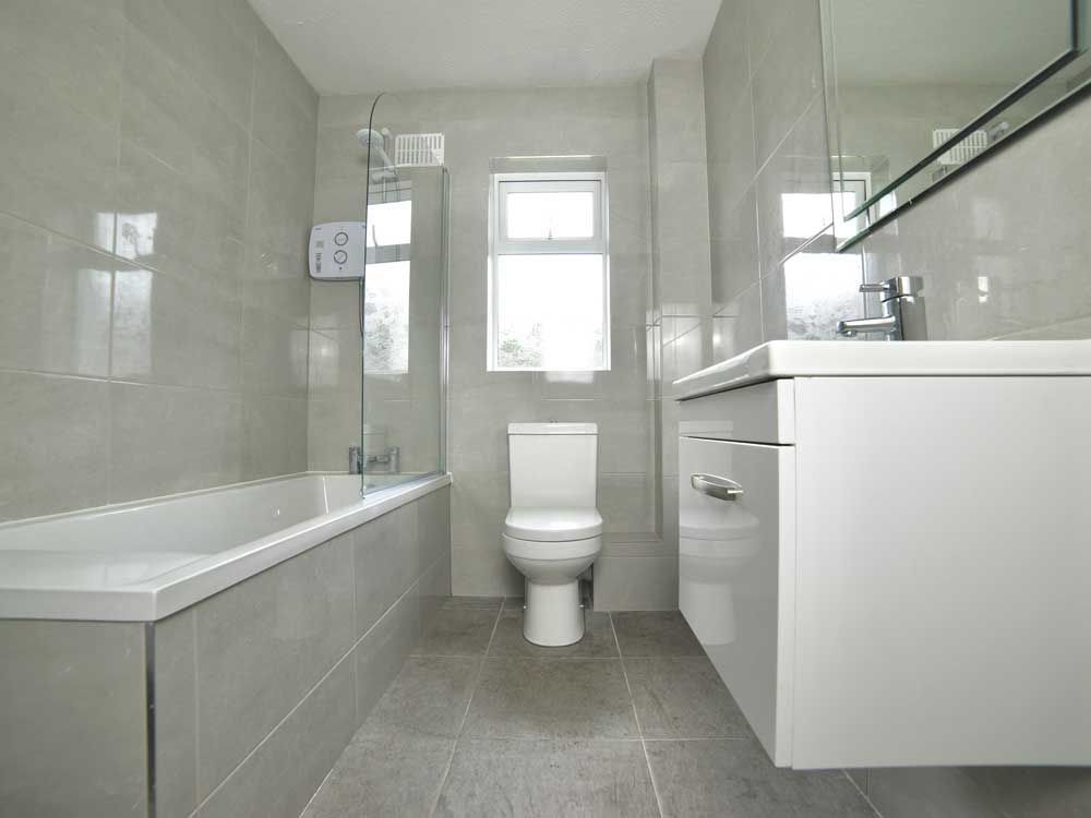 A bathroom with a toilet , sink , bathtub and mirror.