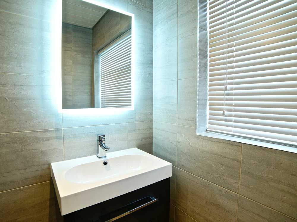 A bathroom with a sink , mirror and blinds.