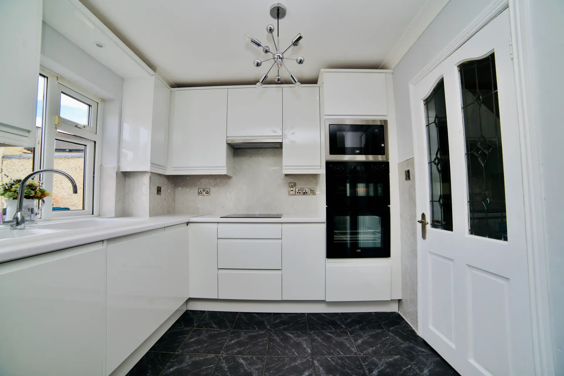 A kitchen with white cabinets and a black floor