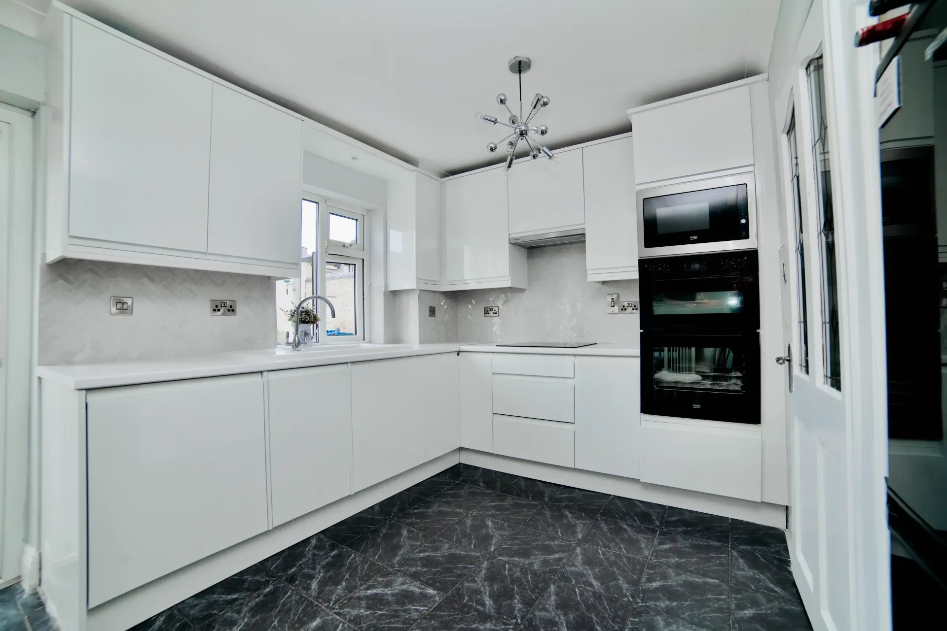 A kitchen with white cabinets and a black floor.
