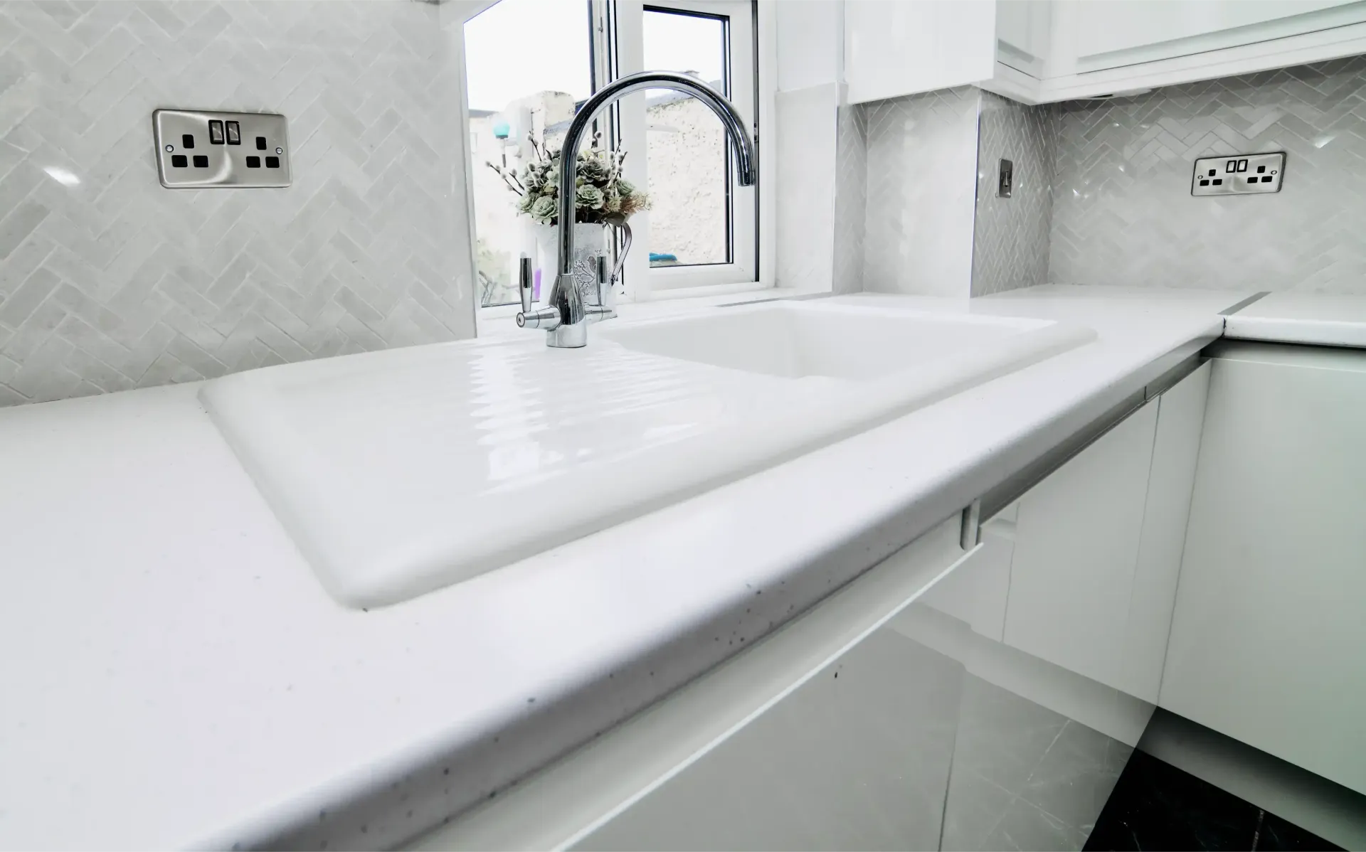 A kitchen sink with a faucet and a window in the background.