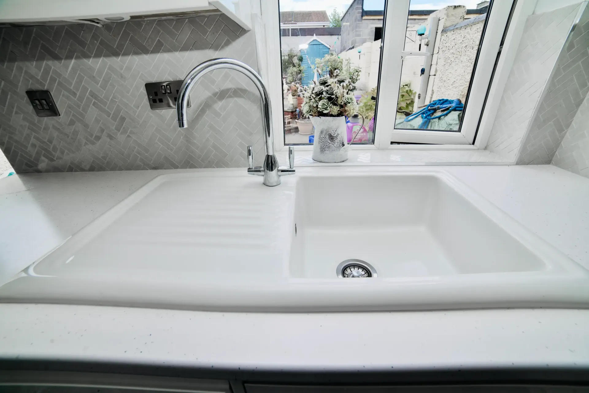 A kitchen sink with a faucet and a window in the background.