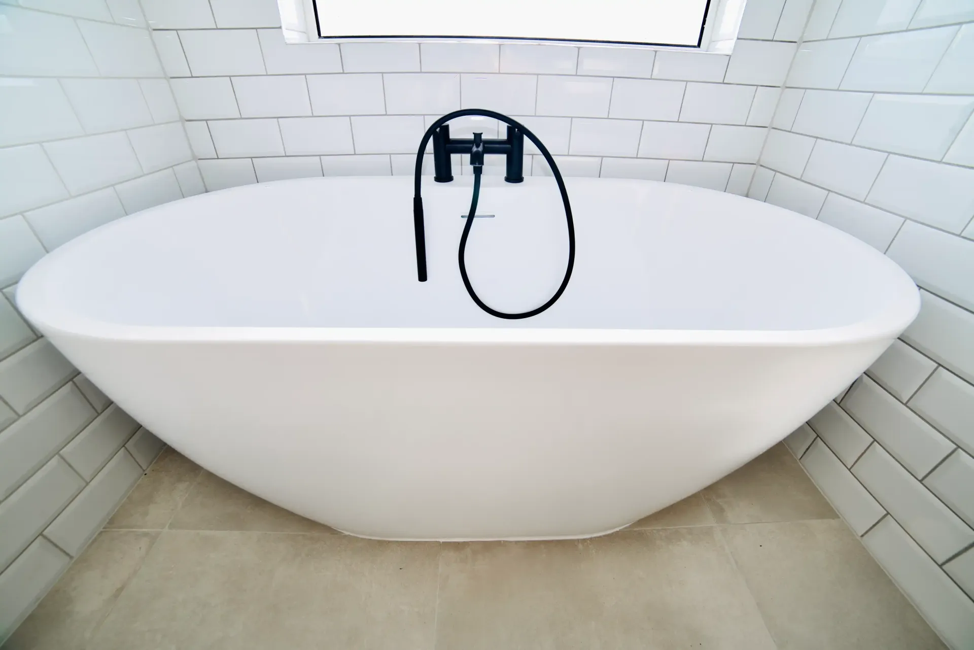 A white bathtub in a bathroom with white brick walls