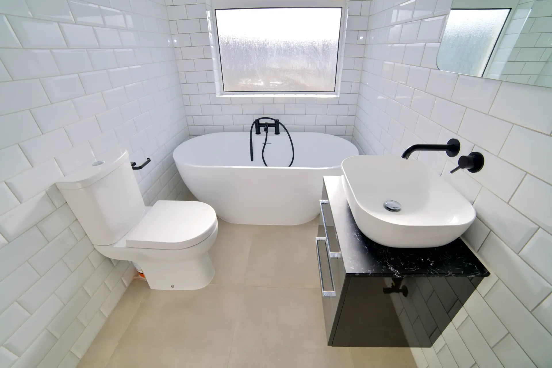 A bathroom with a bathtub , toilet , sink and window.