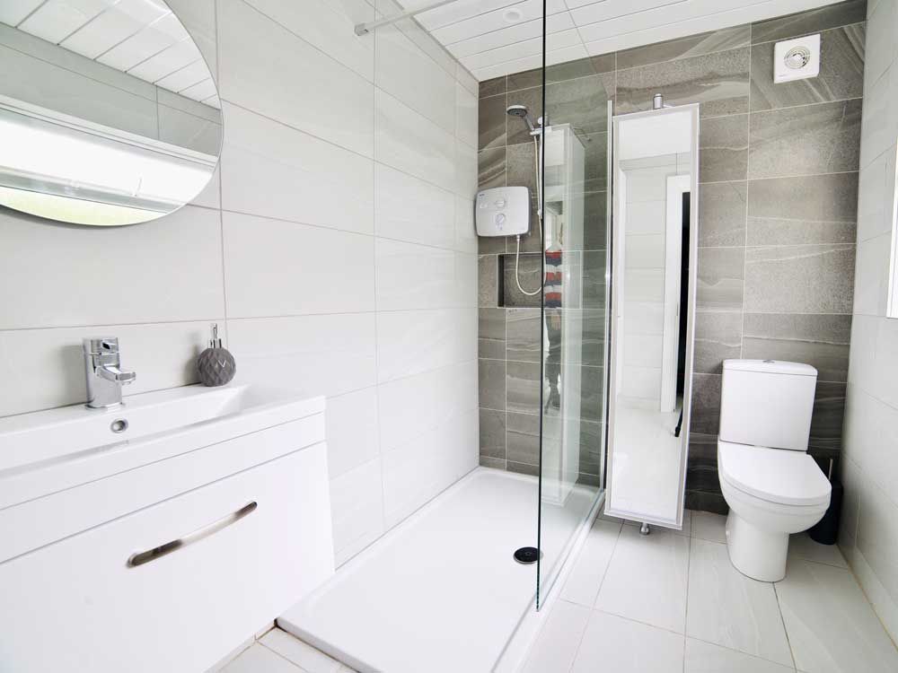 A bathroom with a toilet , sink and walk in shower.