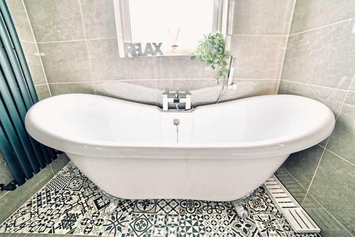 A white bathtub is sitting on a tiled floor in a bathroom.