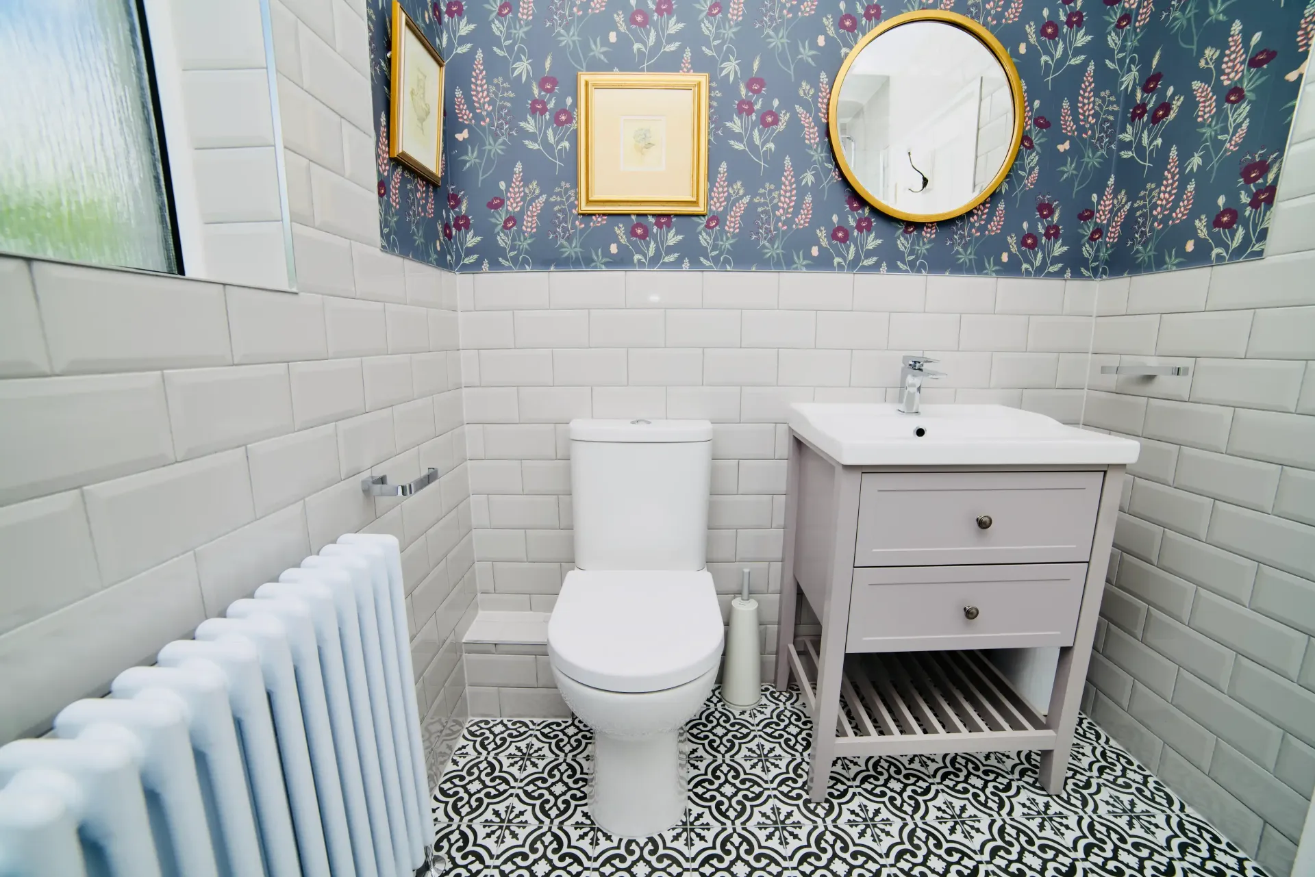 A bathroom with a toilet , sink , mirror and radiator.