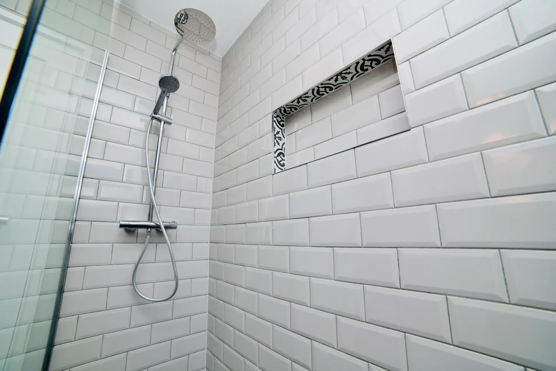 A shower with white tiles and a shower head.