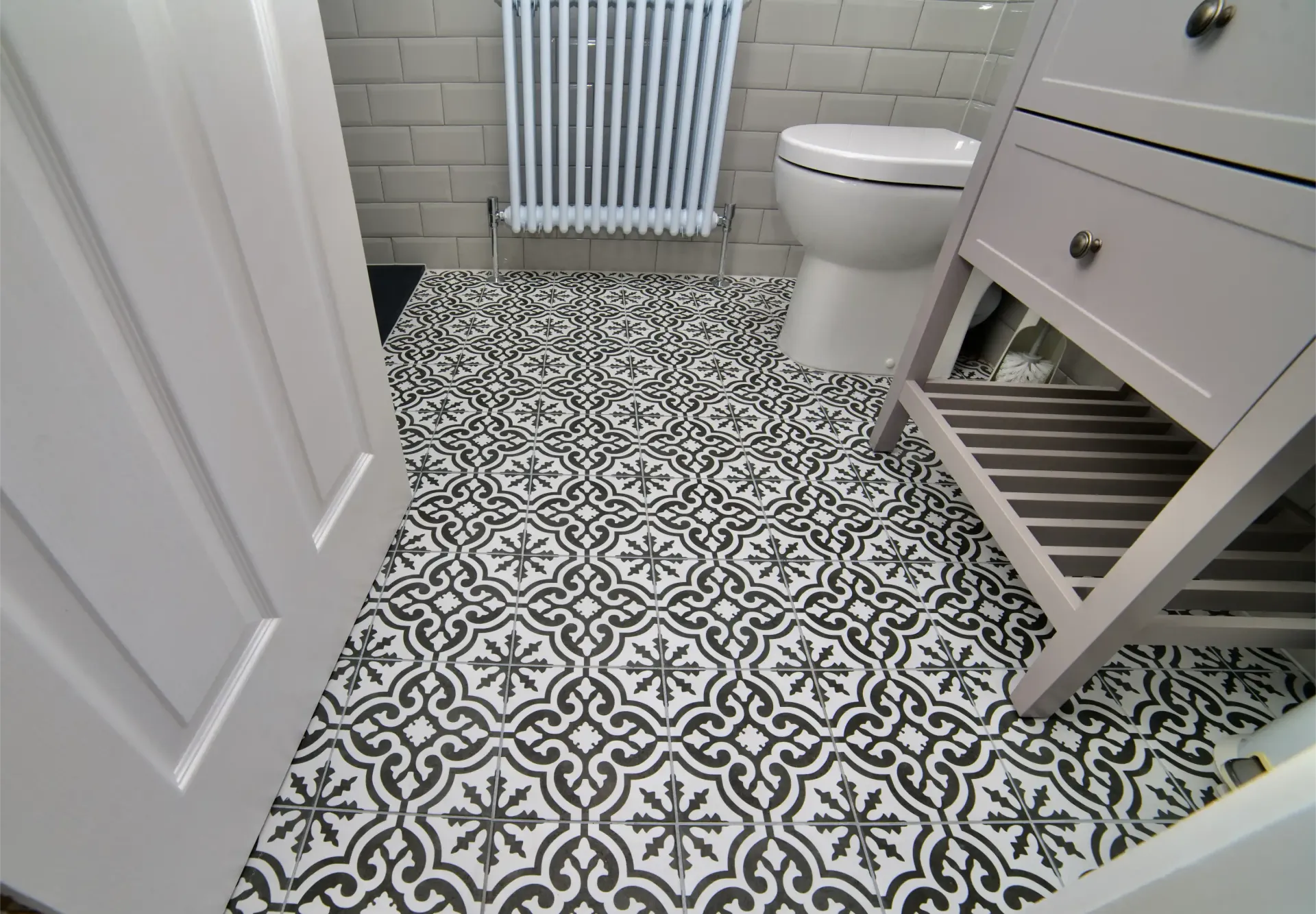 A bathroom with a black and white tile floor and a toilet.