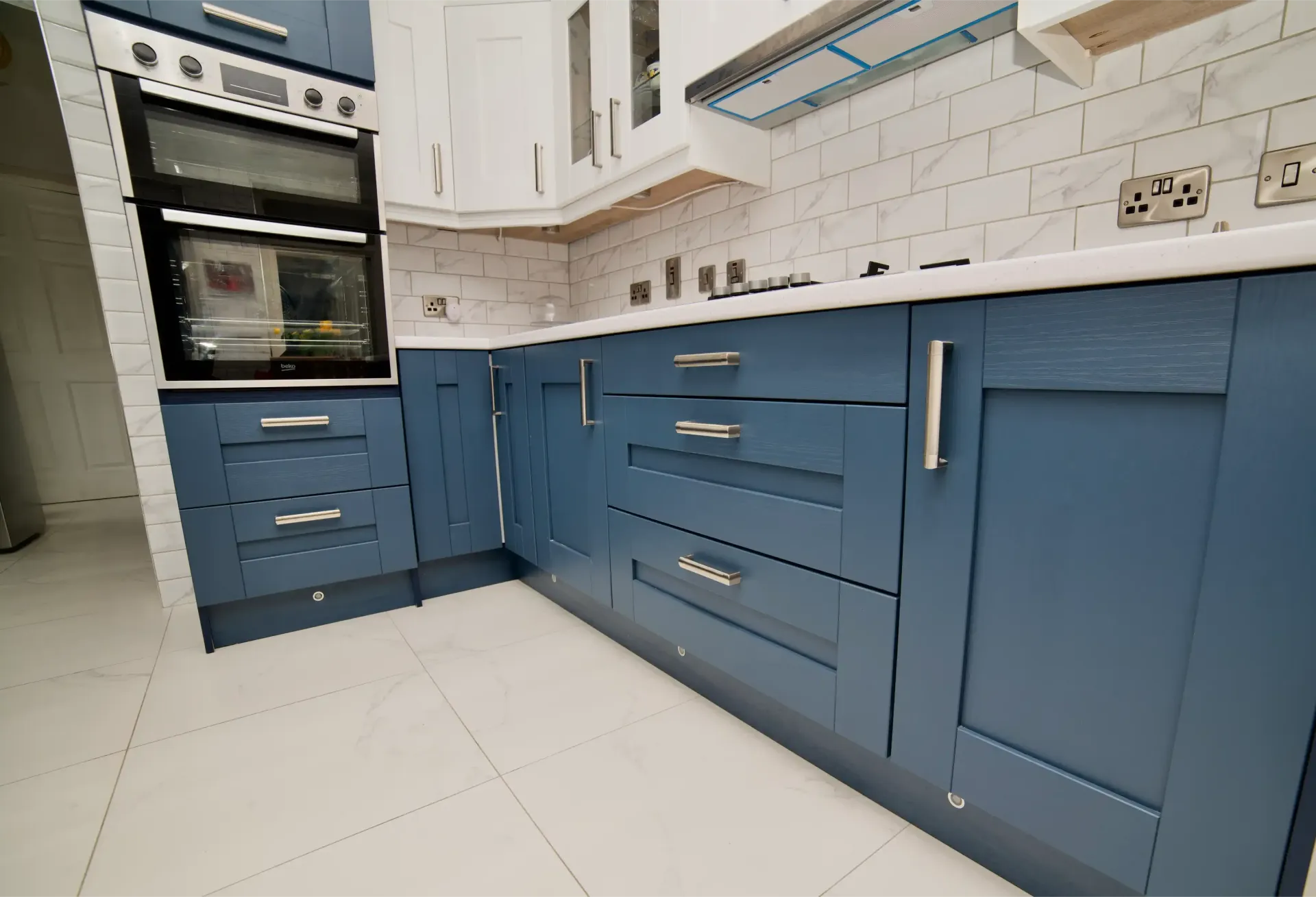A kitchen with blue cabinets and white counter tops
