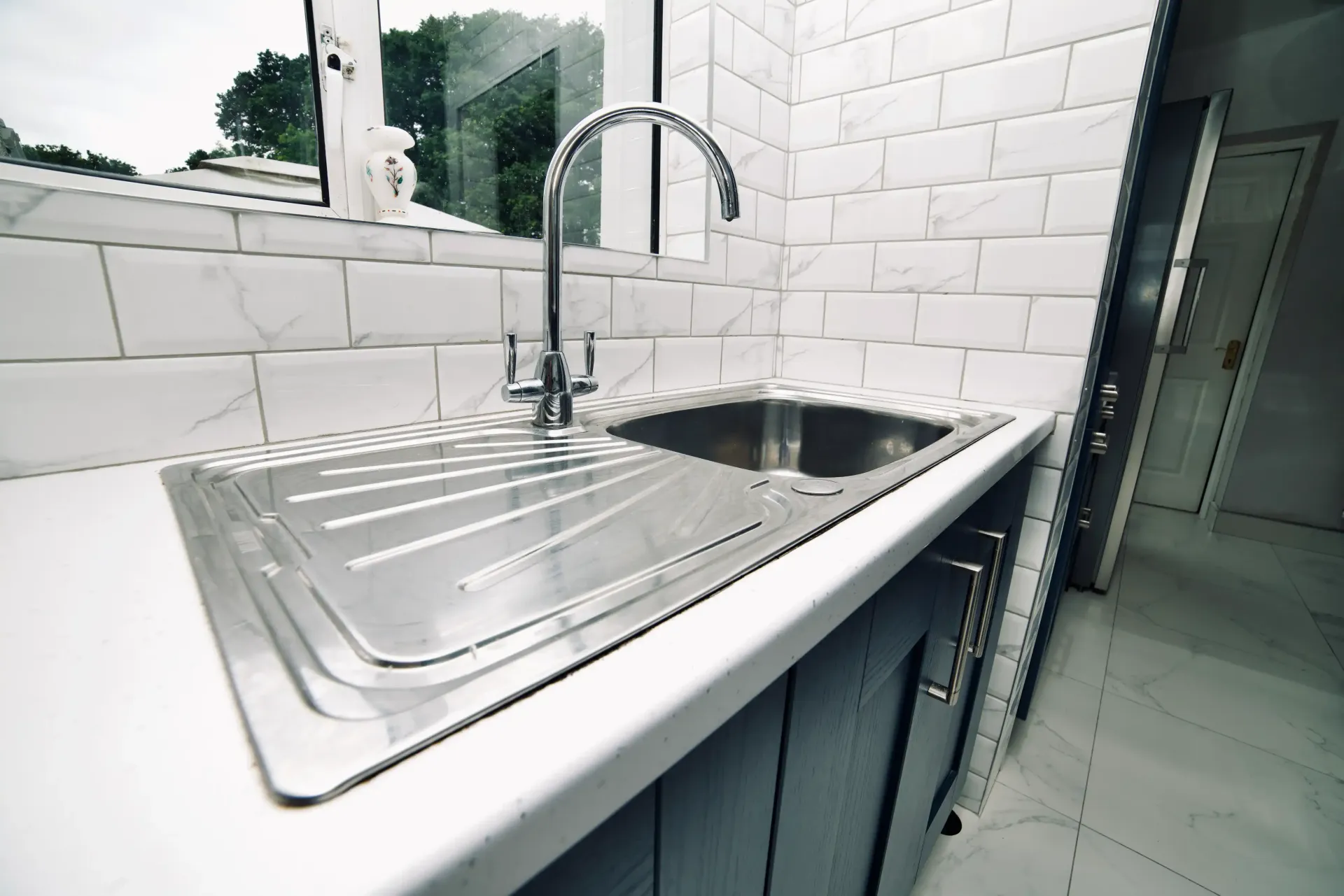 A kitchen sink with a faucet and a window