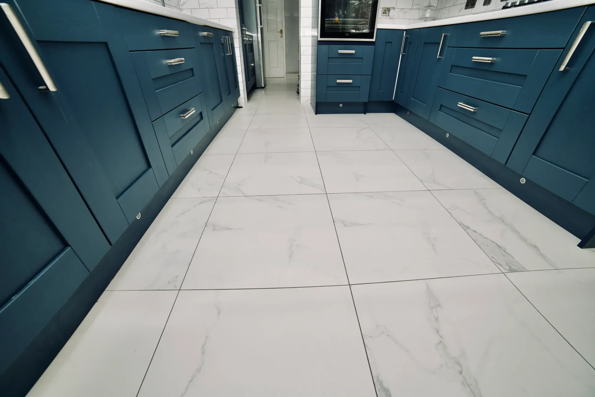 A kitchen with blue cabinets and white tile floors