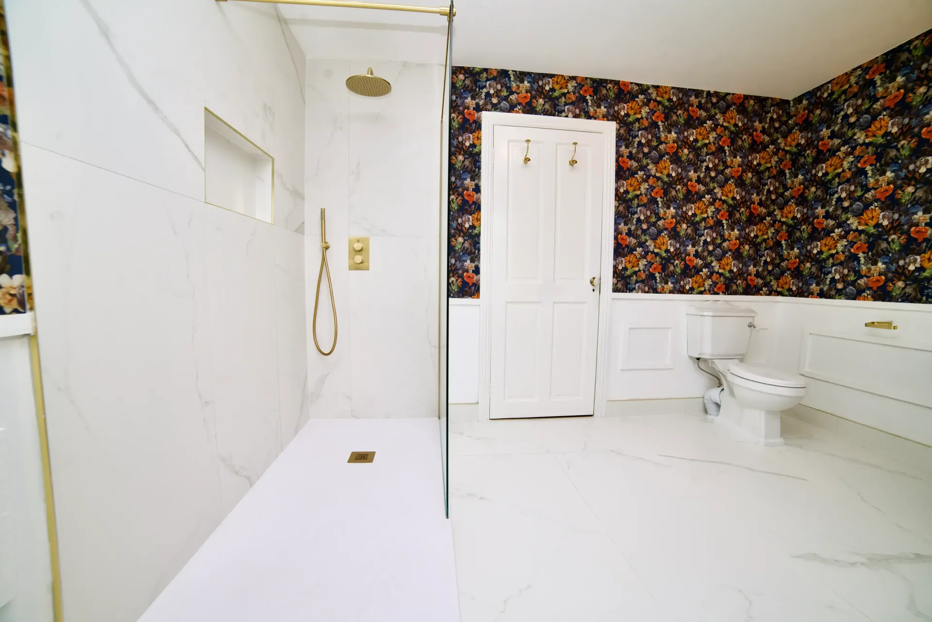 A bathroom with a walk in shower , toilet , and floral wallpaper.