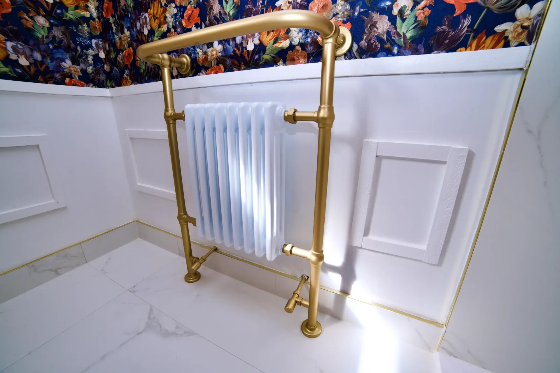A brass towel rack with a white towel on it in a bathroom.