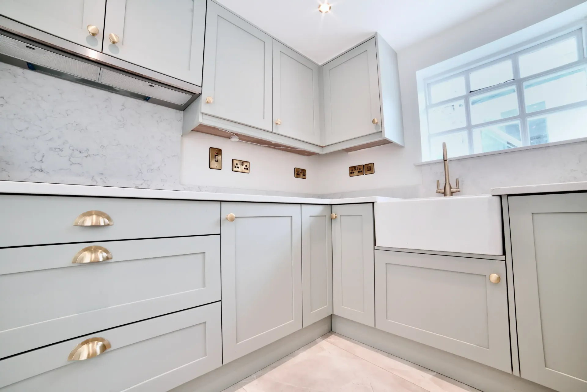 A kitchen with gray cabinets and a white sink