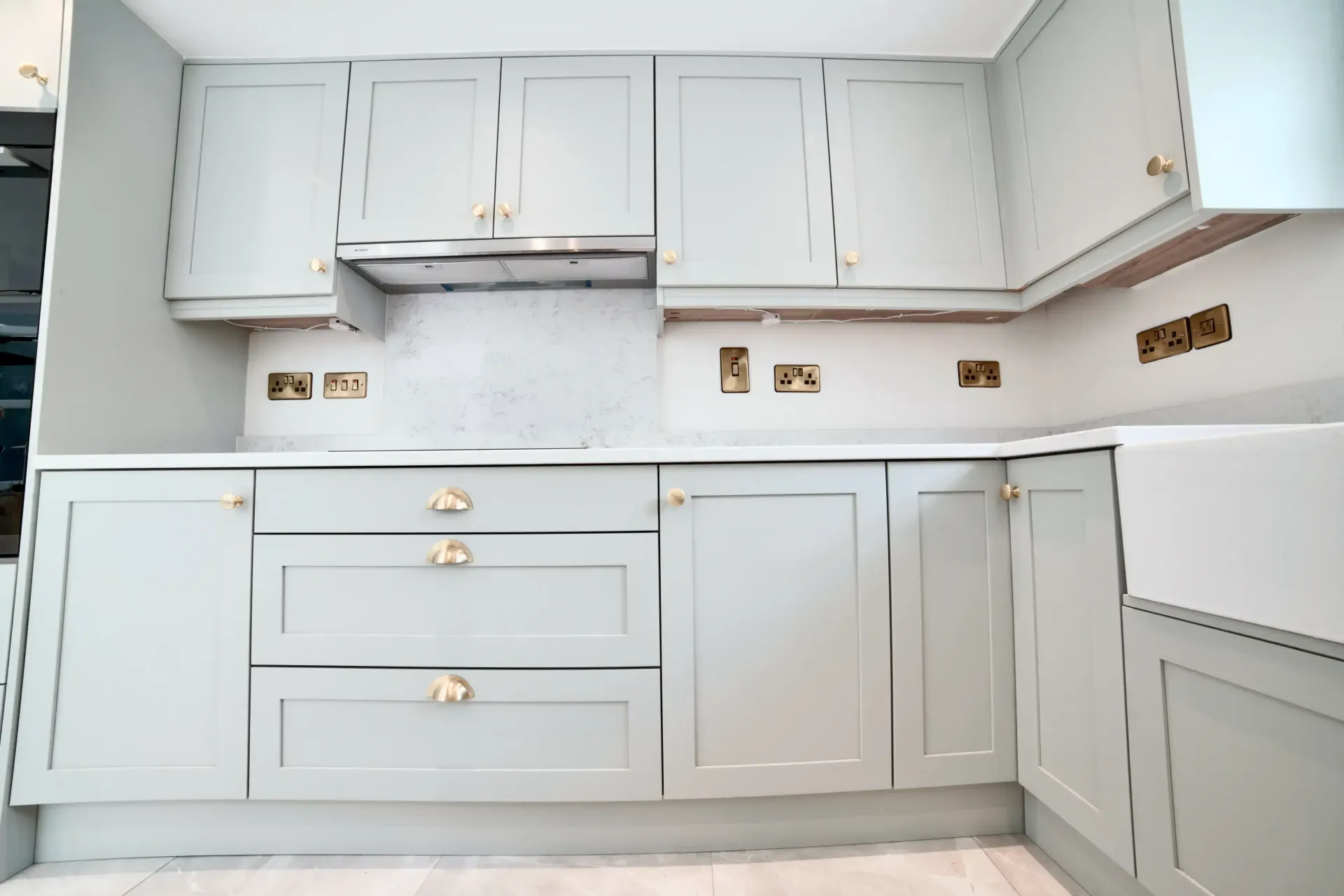 A kitchen with white cabinets and gold handles