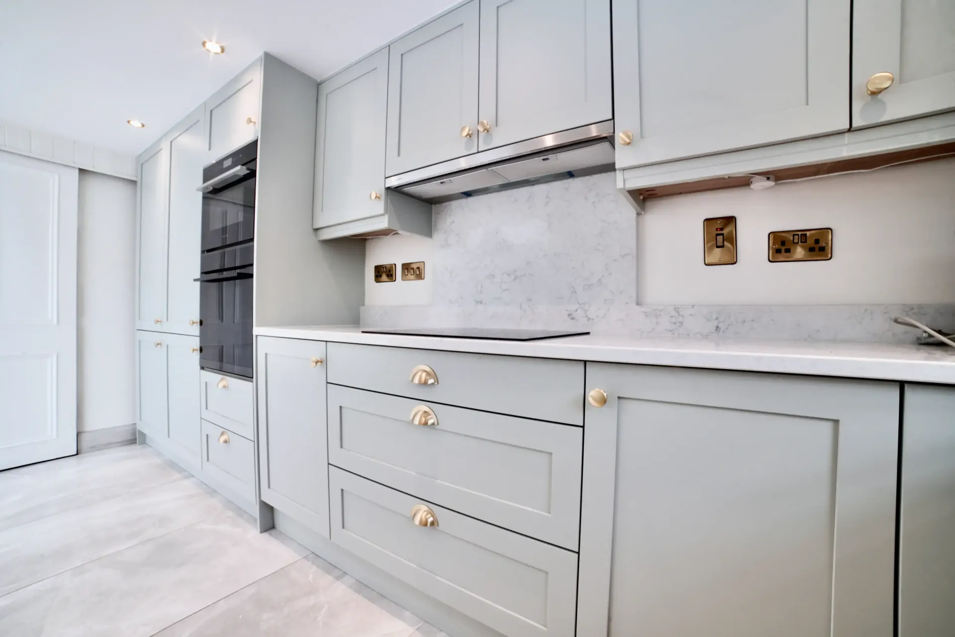 A kitchen with gray cabinets and white counter tops.
