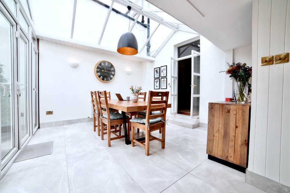 A dining room with a table and chairs and a clock on the wall.