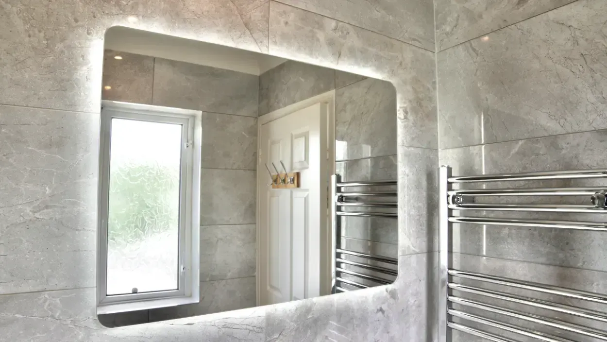 A bathroom with a large mirror and a towel rack.